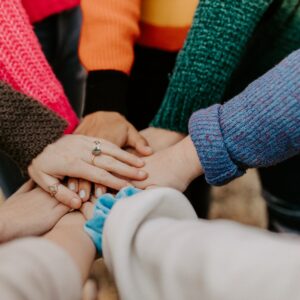People standing in a circle with their hands together in the center